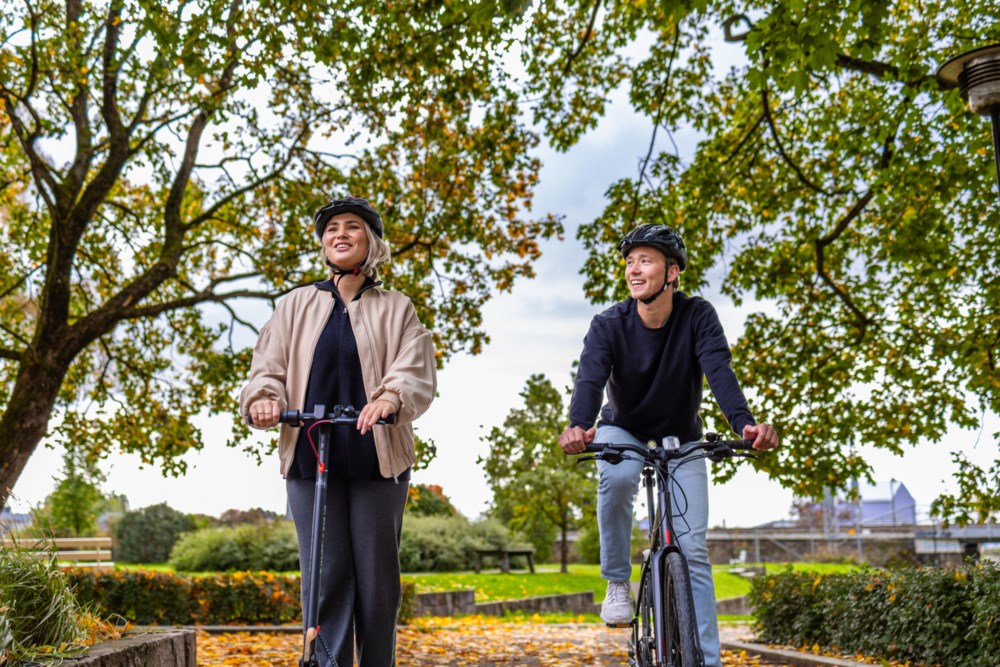 Ung jente på elsparkesykkel og ung gutt på sykkel