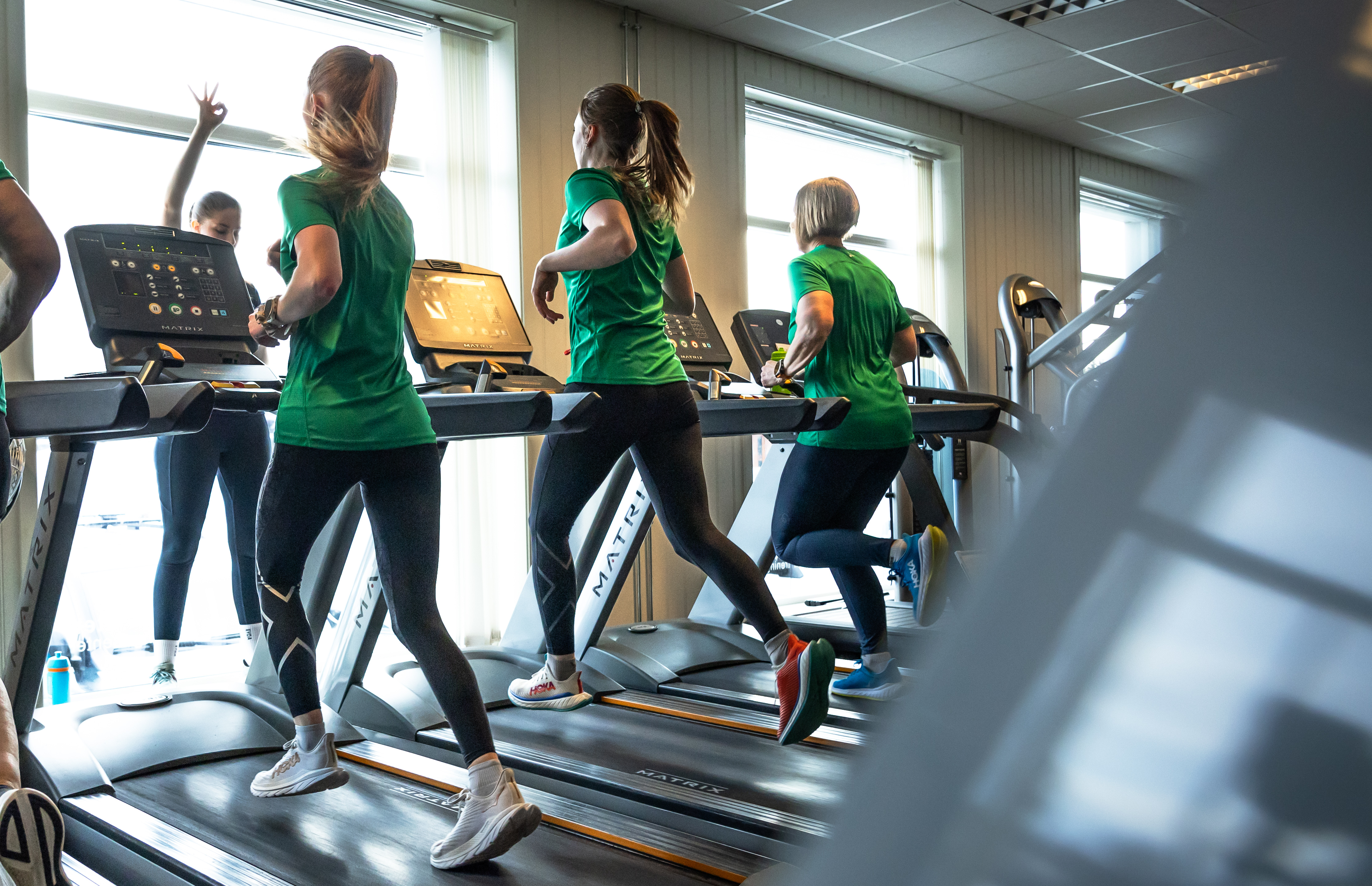 Tre damer som løper på tredemølle, alle har på seg grønne t-skjorter