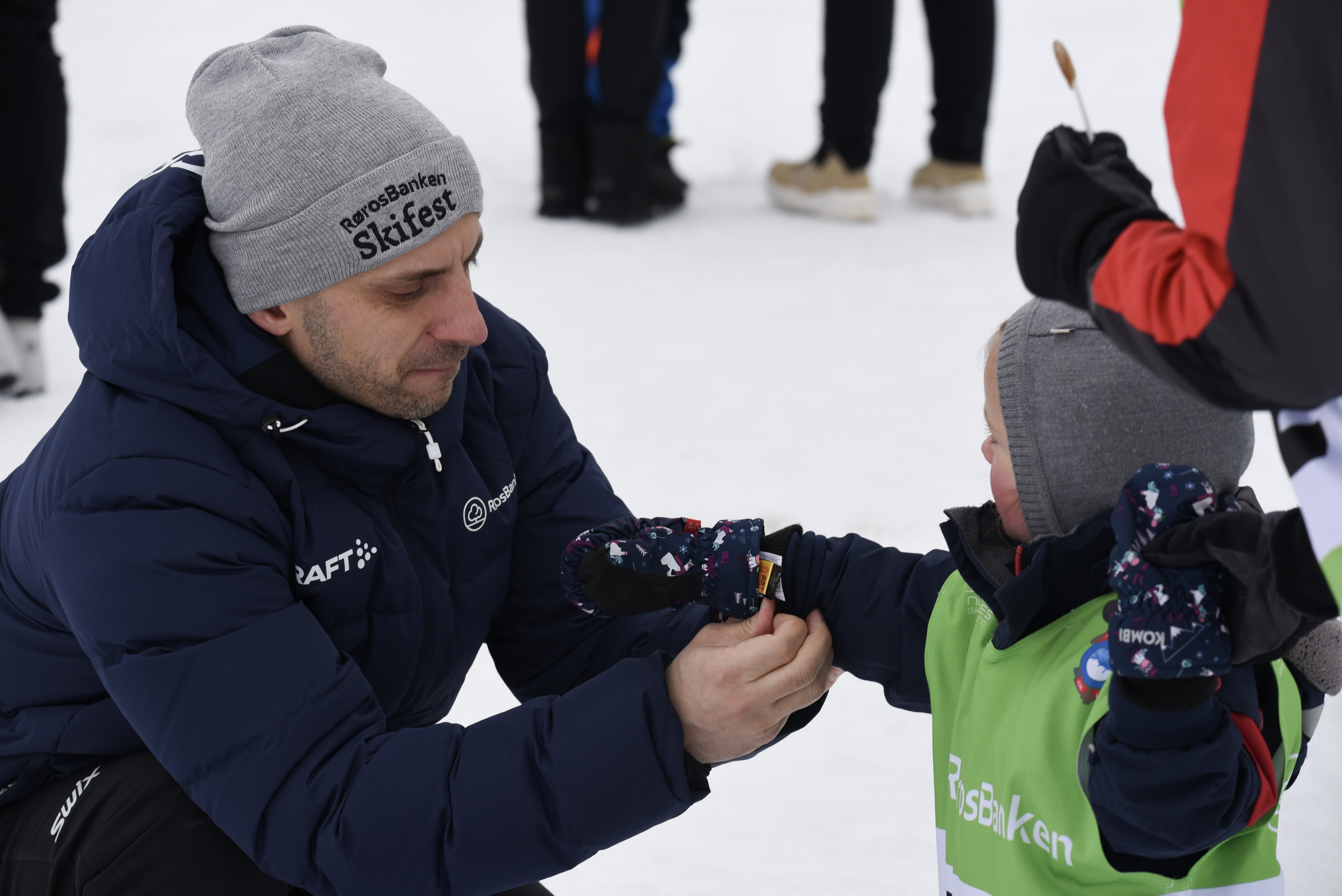 Mann hjelper lite barn med å ta på vott
