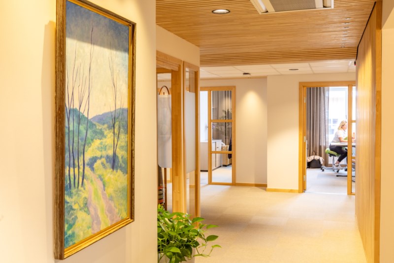 bildelokale av en gang, med kunst på veggen. Dame som jobber på kontorplass i bakgrunnen