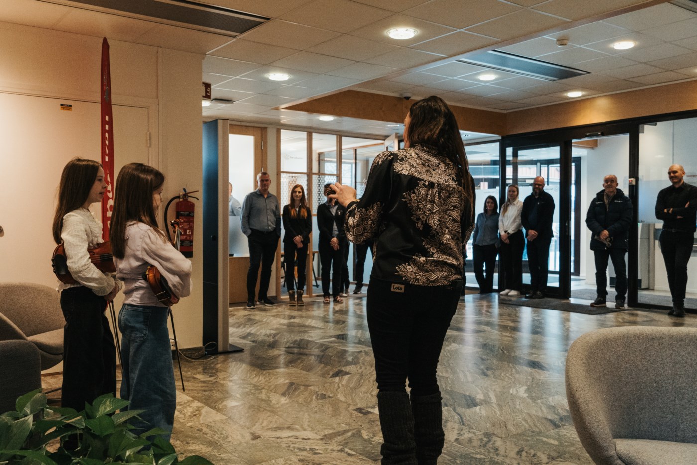 Bilde av tre felespillere som holder konsert i resepsjonen i RørosBanken