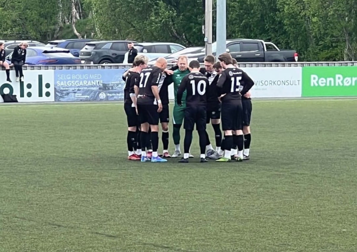 Fotballag som står sammen i ring på banen.